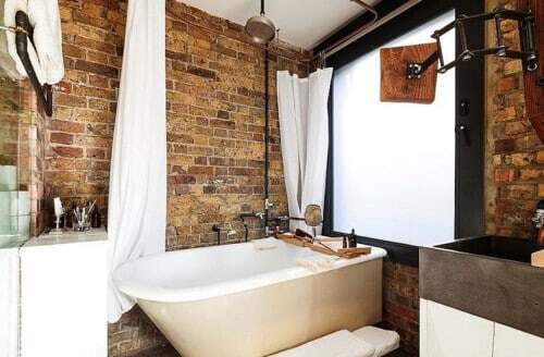 Bagno nuovo con vasca su parete in mattoni stile antico
