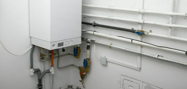 Caldaia murale installata su parete interna con tubazioni idrauliche ordinate e sistema di distribuzione a vista Installazione ordinata di una caldaia murale: l’importanza della qualità impiantistica