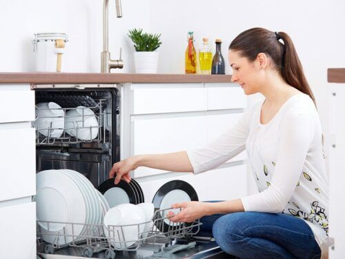 Ritratto di donna felice con la sua nuova lavastoviglie in cucina