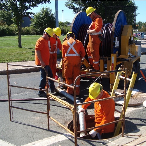 immagine di una squadra di professionisti impegnata in operazioni di ispezione e manutenzione di un tombino