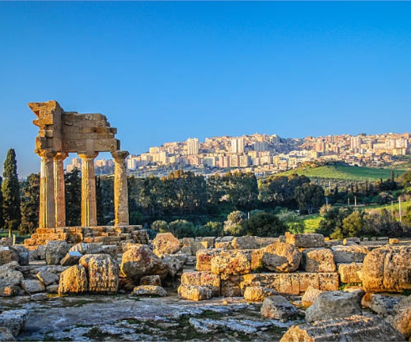 Le case ad Agrigento sullo sfondo delle rovine di un tempio antico.