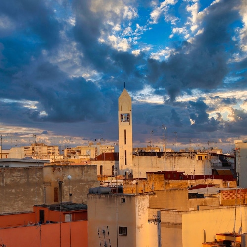 Immagine di un campanile nel centro cittadino tra le casa a Barletta.