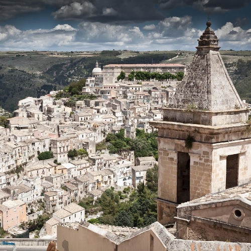 Vista panoramica sulle case a Ragusa nel centro storico con chiese barocche e paesaggio collinare.