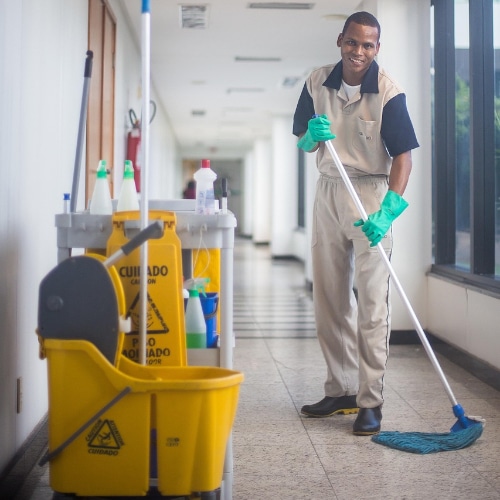 Addetto pulizie condominiali con attrezzatura professionale.