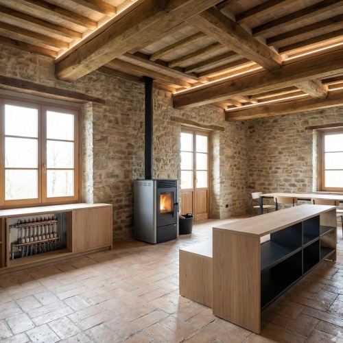 Un'immagine che cattura l'essenza di un recupero conservativo di un'ex stalla italiana. L'autenticità delle pareti in pietra e delle travi in legno si fonde armoniosamente con l'efficienza energetica, rappresentata dalla stufa a pellet e dal sistema di riscaldamento a pavimento integrato. L'arredamento minimalista e l'illuminazione a LED incassata esaltano l'architettura storica senza sovrastarla, creando un ambiente accogliente e sostenibile.