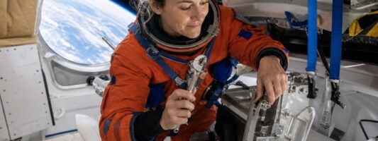 Astronauta donna ripara il bagno spaziale della capsula Orion durante la missione Artemis II verso la Luna.