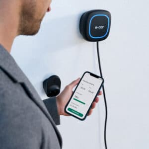 Persona che controlla una wallbox domestica per auto elettrica tramite smartphone.