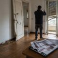 Casa devastata dopo lo sfratto con parquet e porte danneggiati.