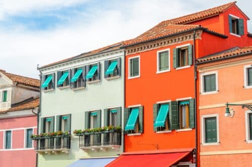 Facciate colorate di edifici storici con persiane e tende da sole