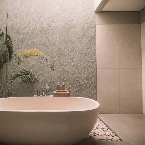 Vasca stand alone in un bagno moderno e minimal dall'atmosfera calda e materica. Colori bagno tendenze 2026 per rivestimenti, sanitari e accessori.